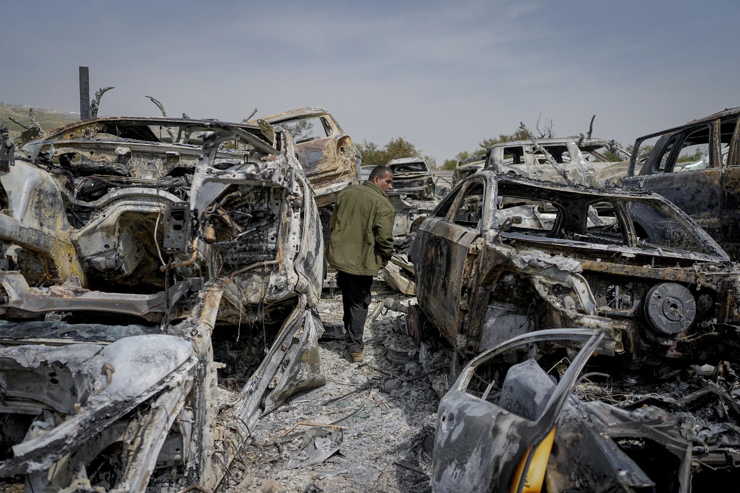 A Palestinian man walks between cars burnt down by Zionist settlers in the town of Huwara, occupied West Bank, Palestine, February 27 2023. (AP)