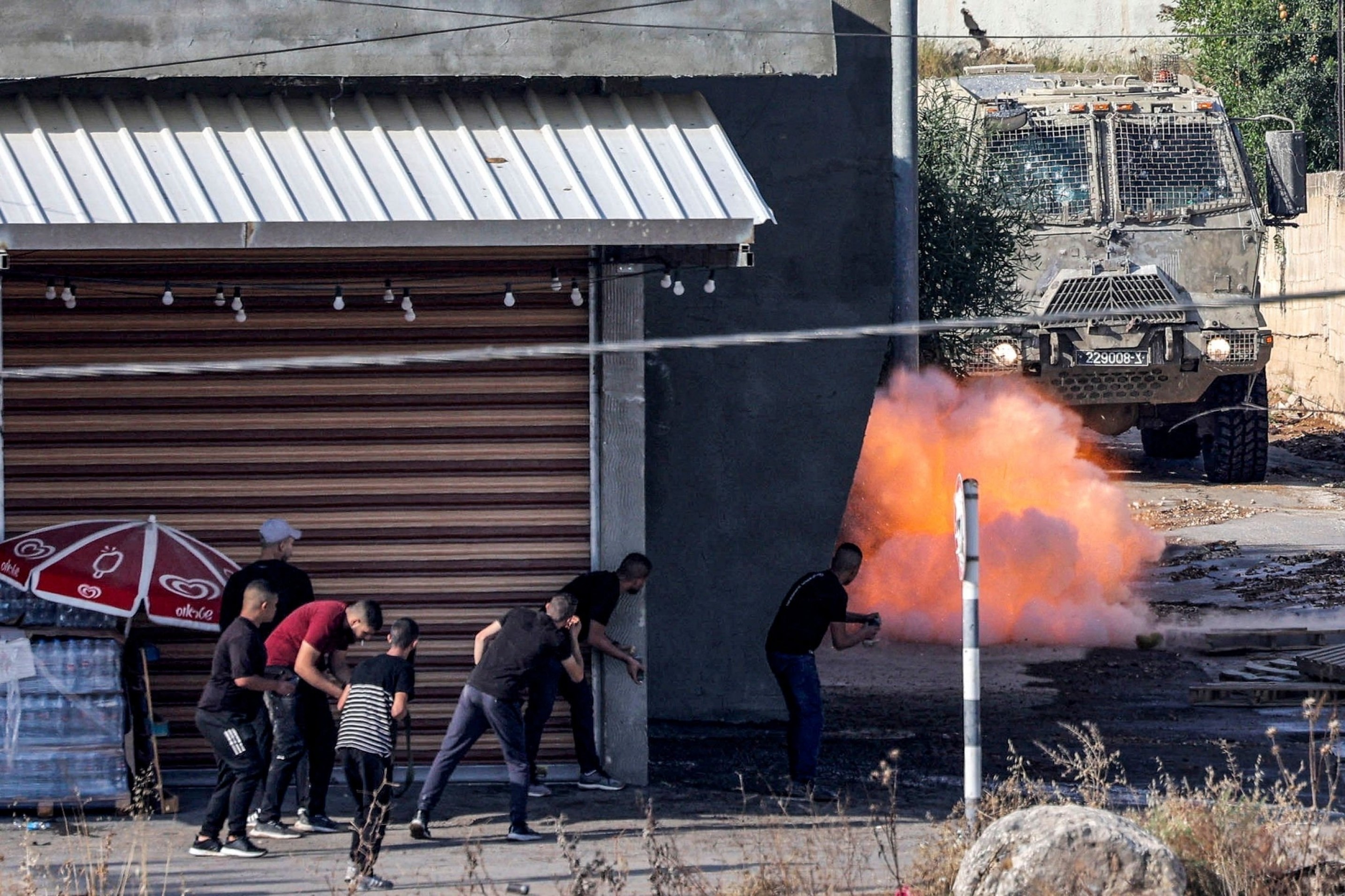 An explosive charge detonates in front an Israeli Armored Personnel Carrier (APC) as local fighter shoot towards it, Jenin, in the occupied West Bank, Palestine, June 19 2023. (AFP)