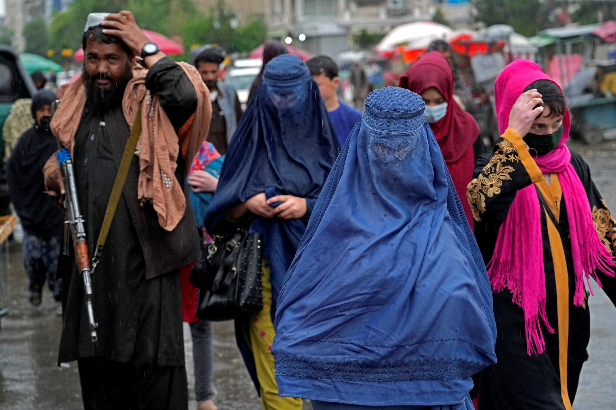 Afghan women walk through the old market as a Taliban fighter stands guard, in downtown Kabul, Afghanistan, May 3, 2022. (AP)