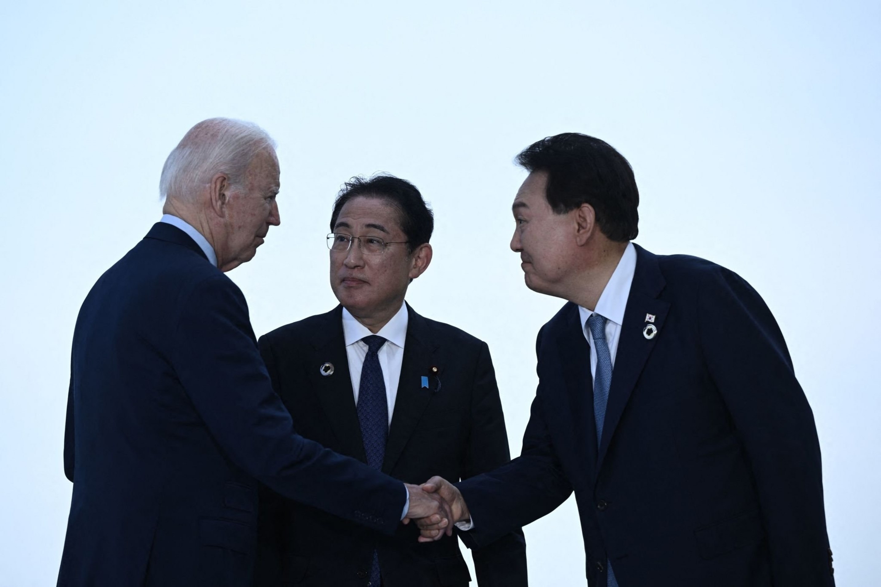 US President Joe Biden shakes hands with Japan's Prime Minister Fumio Kishida, in the presence of South Korea's President Yoon Suk Yeol ahead of a trilateral meeting during the G7 Leaders' Summit in Hiroshima, Japan, May 21 2023