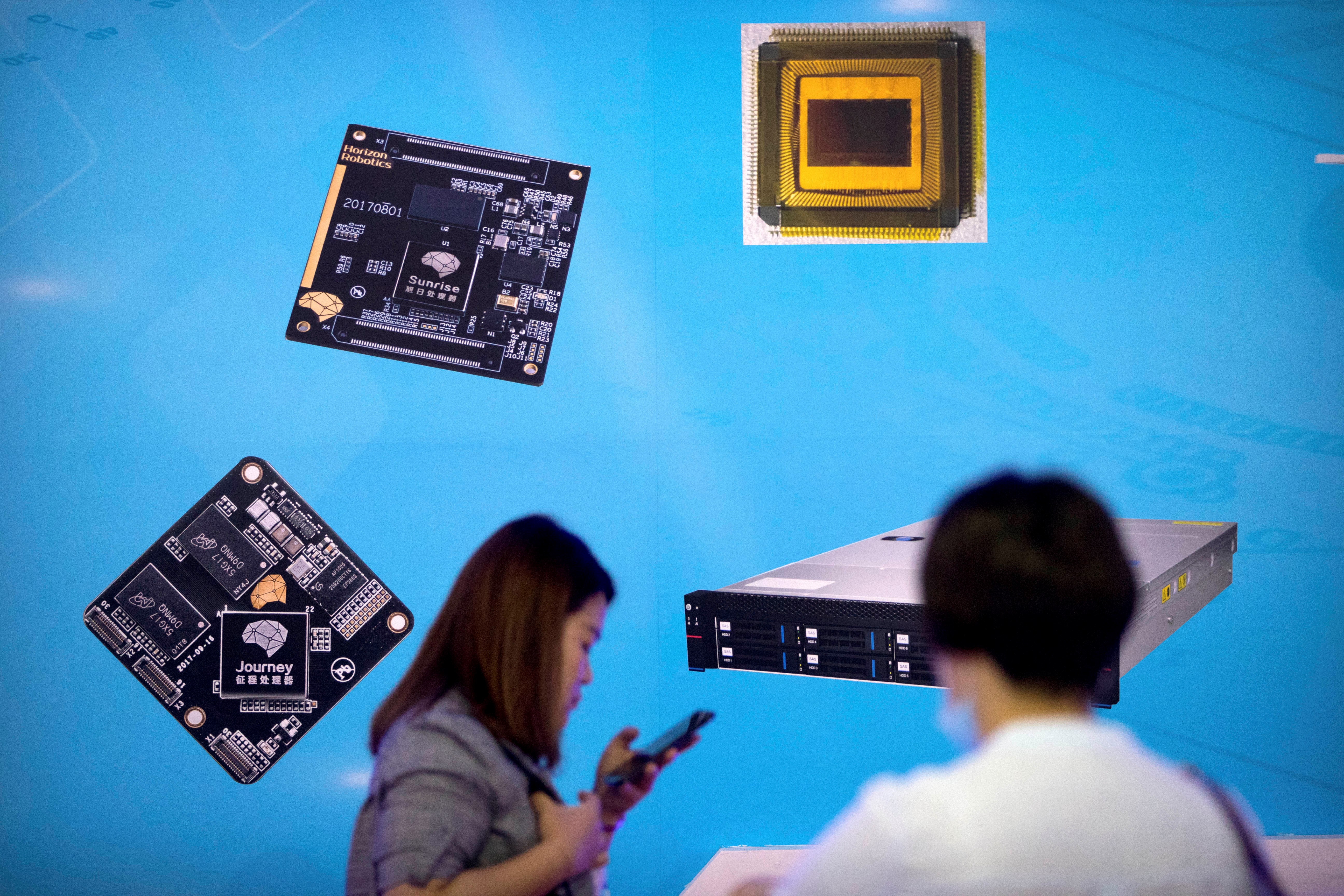 Visitors walk past a display showing microchips and circuit boards at the 21st China Beijing International High-tech Expo in Beijing, China, Friday, May 18, 2018 (AP Photo/Mark Schiefelbein)