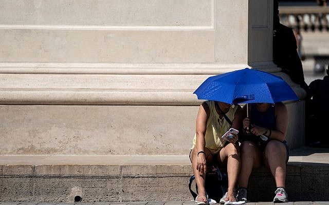 People use an umbrella to shelter from the sun near the Louvre Pyramid (Pyramide du Louvre) during a heatwave in Paris on June 26, 2019. (AFP)