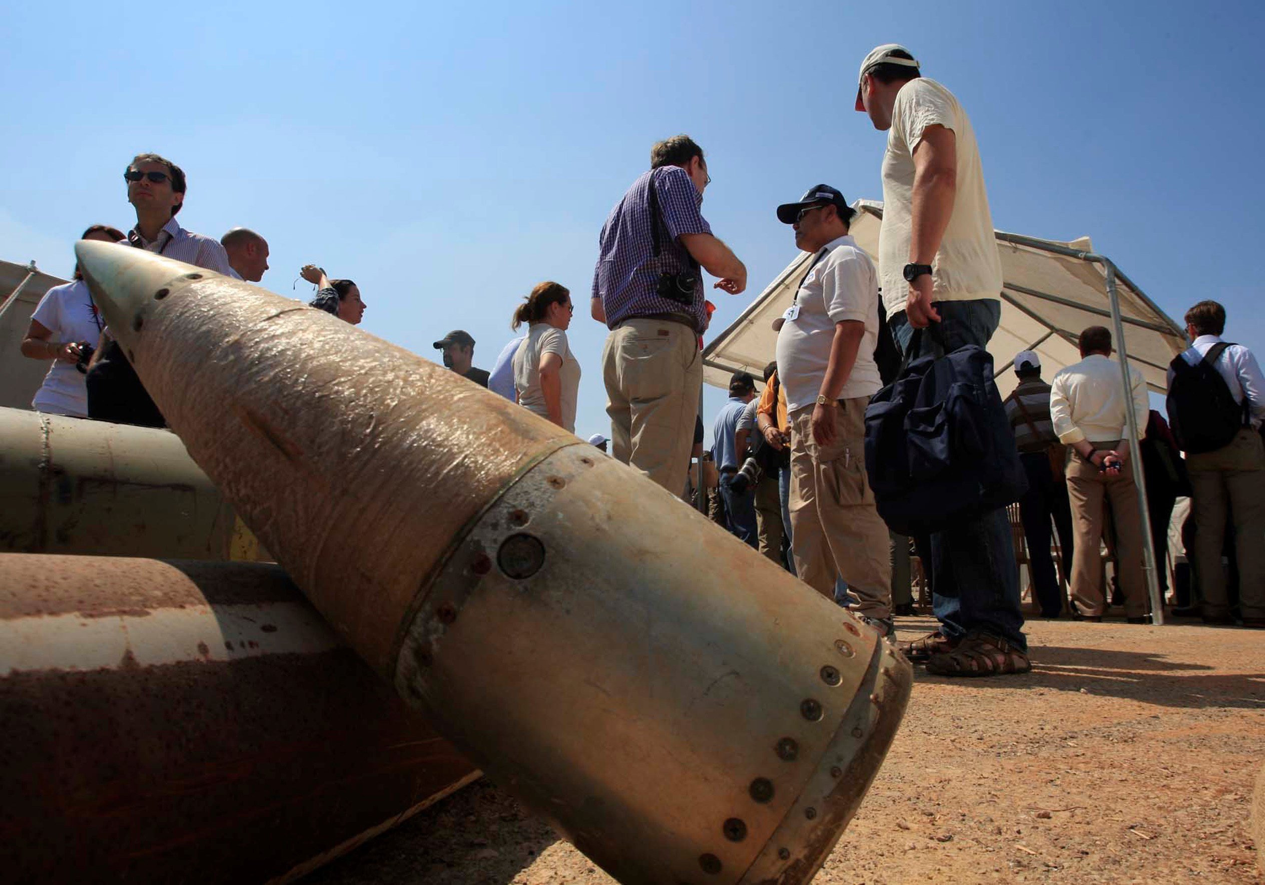 Activists and international delegations stand next to cluster bomb units (AP)