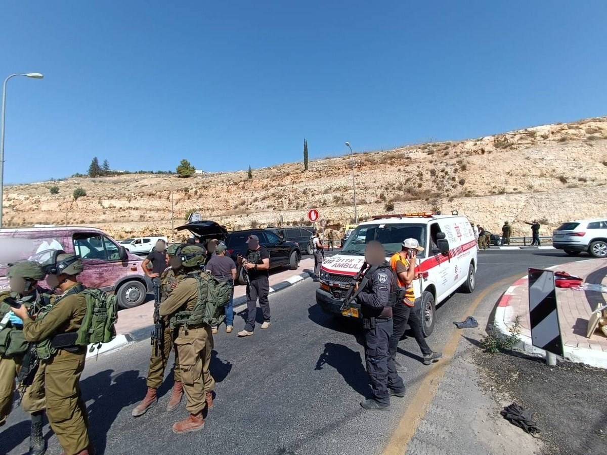 Settlers and IOF forces stand around the scene of a shooting operation near the Israeli settlement of Tekoa.