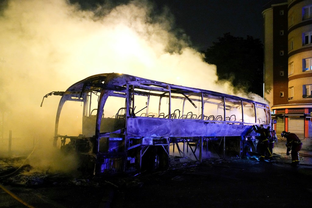 Firefighters use a water hose on a burnt bus in Nanterre, outside Paris, France, Saturday, July 1, 2023 (AP Photo/Lewis Joly)