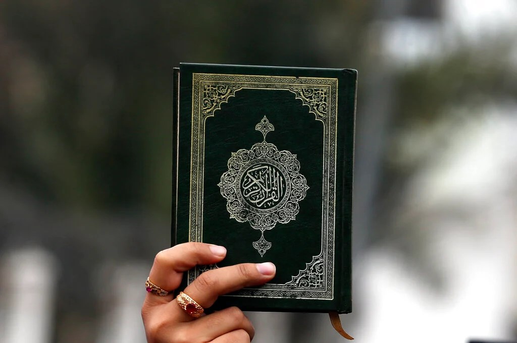 A man carrying the holy Quran during a protest (AP)