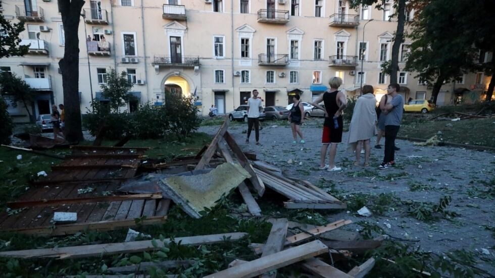 People stand among the debris outside a residential building after a missile strike in Odesa early in the morning of July 23, 2023 (AFP)