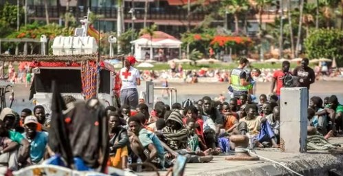 Migrants rest on the pier after disembarking from a 'cayuco' (wooden boat) following a rescue operation on July 4, (AFP)