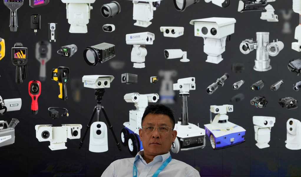 A vendor sits near a board depicting surveillance cameras during Security China 2023 in Beijing, on June 9, 2023. (AP)