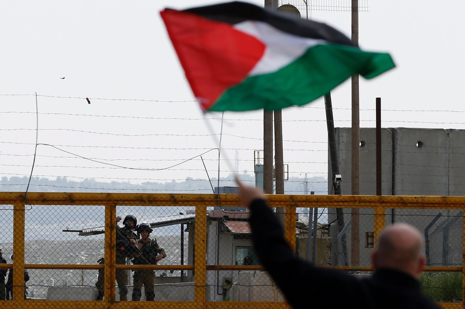 A Palestinian protestor waves his Palestinian flag infront of Israeli Occupationa Ofer prison near Betunia in the Israeli occupied West Bank, March 30, 2016. (AFP)