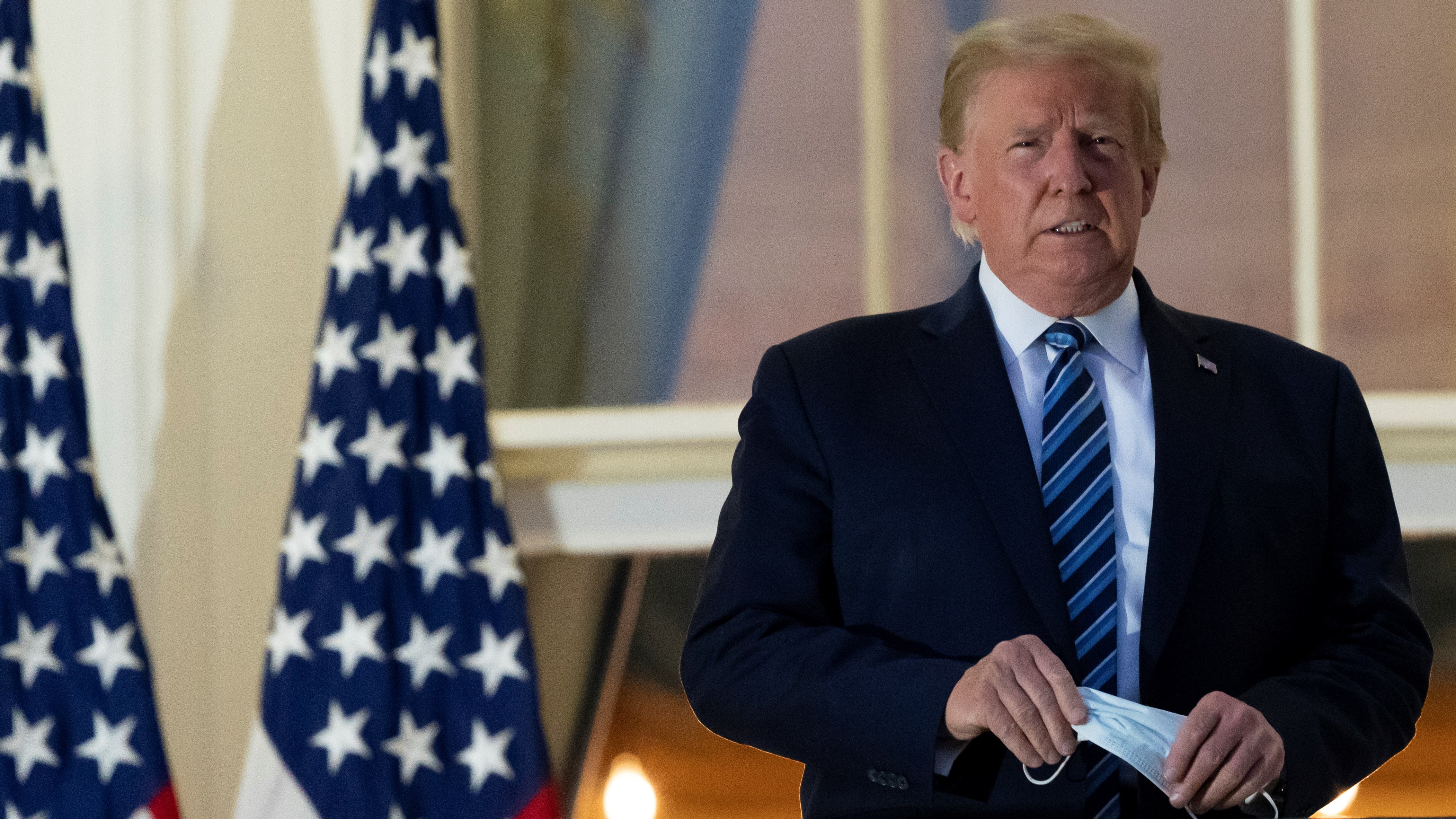 President Trump holds his face mask as he stands on the Blue Room Balcony at the White House in October 2020 (AP)