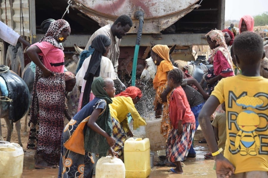 Sudanese refugees from the Tandelti area fill containers and drink from a water tank in Koufroun, Chad, near Echbara, on April 30, 2023. (AFP)