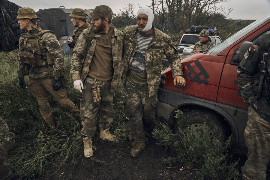 A Ukrainian soldier helps a wounded soldier on the road in the freed territory in the Kharkiv region, Ukraine, Monday, Sept. 12, 2022. (AP)