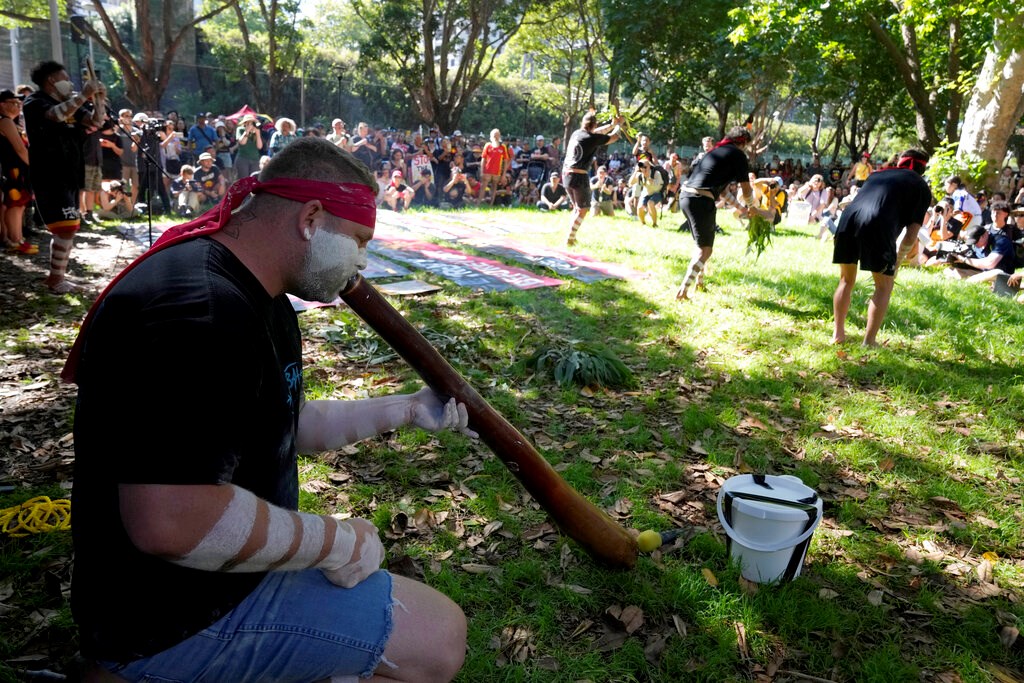 Aboriginal man Arron Nichols, left, plays a didgeridoo as other members of the Muggera Dancers perform at the start of an Invasion Day rally in Sydney, Thursday, Jan. 26, 2023 (AP Photo/Rick Rycroft)