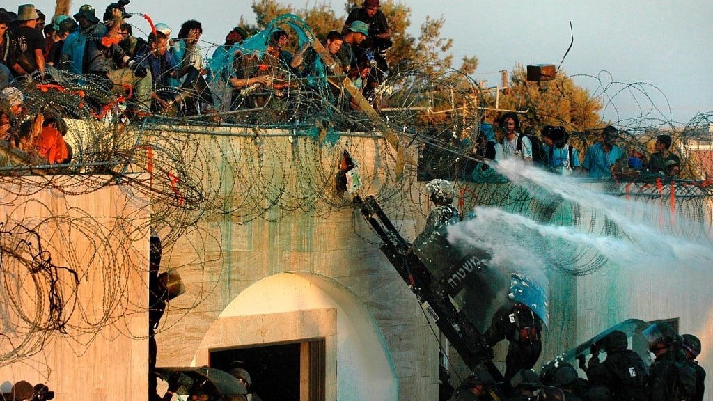 Israeli soldiers prepare to remove settlers from a roof at the settlement of