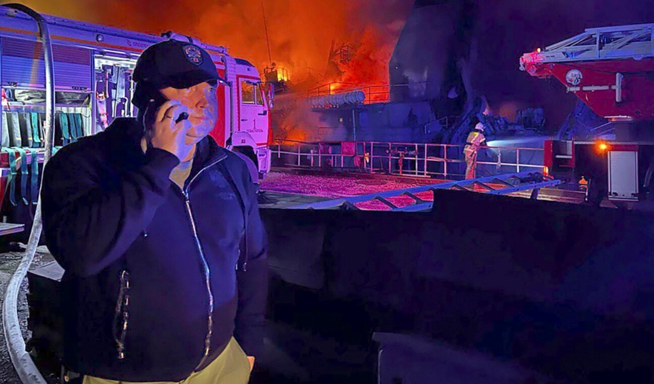 The Governor of Sevastopol, Mikhail Razvozhaev, is seen speaking on a phone as smoke and flame rise from a burning shipyard in Crimea in this photo posted to Razvozhaev's Telegram channel on Sept. 13, 2023. (AP)
