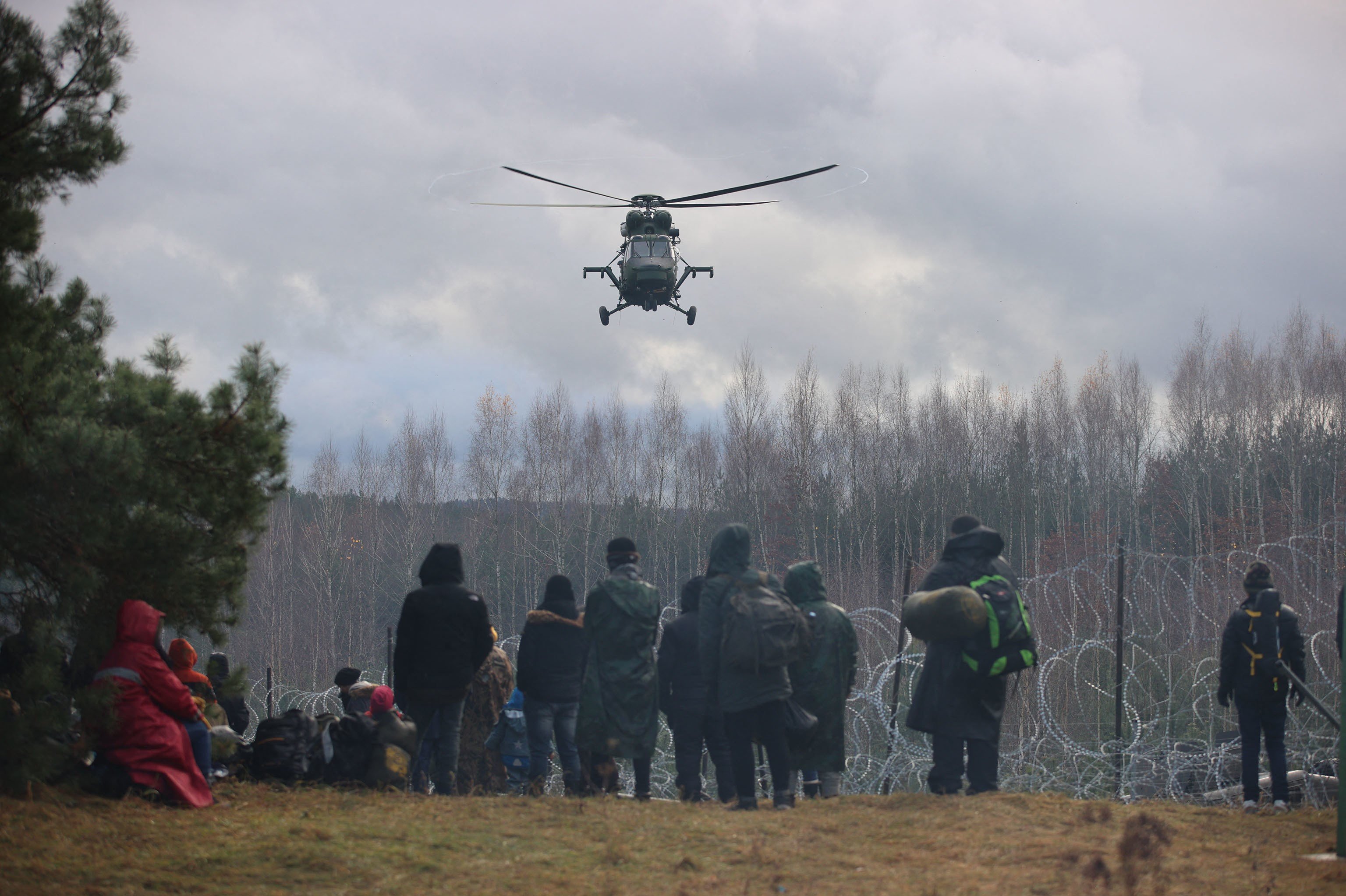 Migrants at the Belarusian-Polish border in the Grodno region, in Belarus, watch a helicopter overhead on Nov. 8. (AFP)