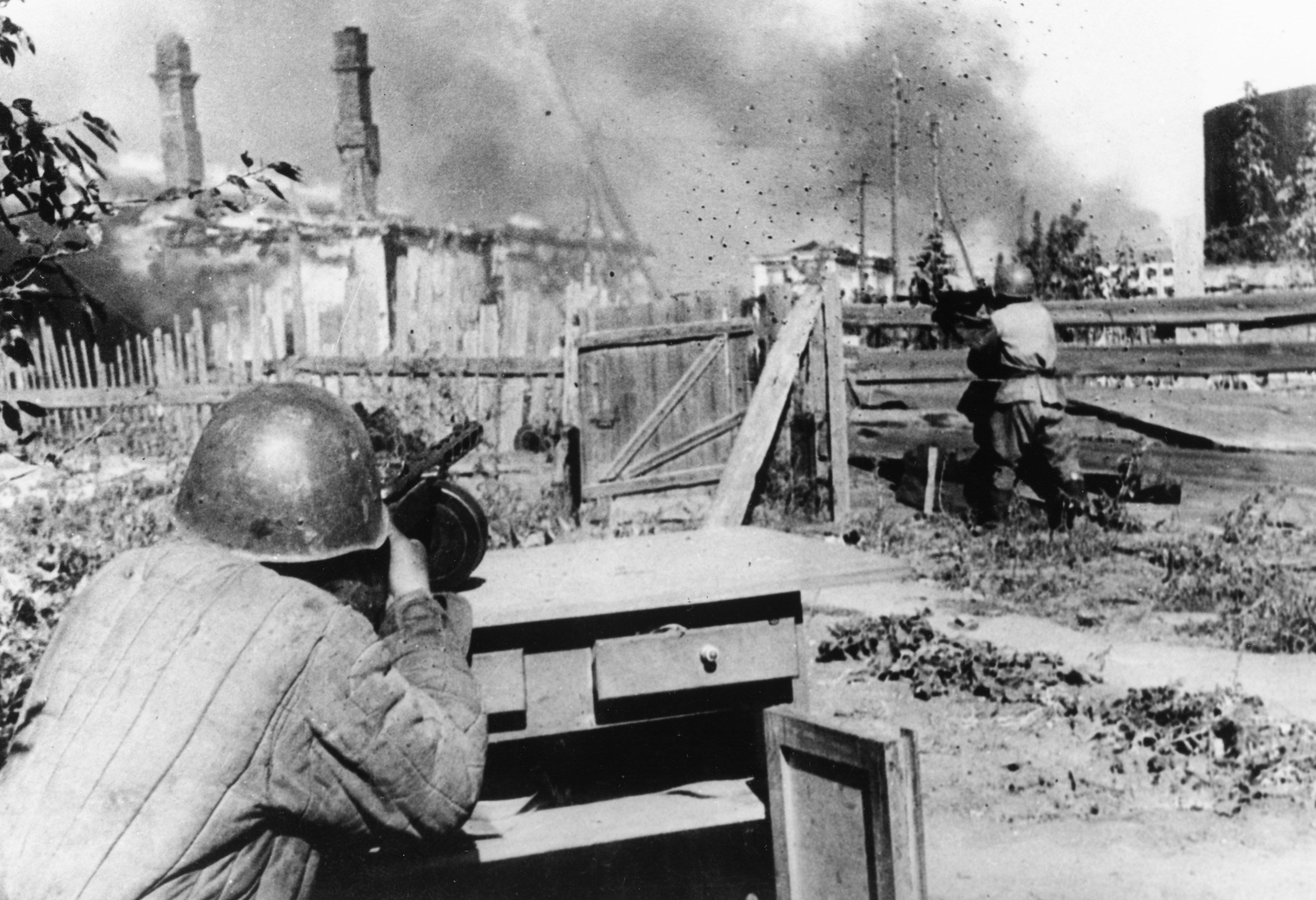 Standing in the backyard of an abandoned house in the outskirts of the besieged city of Leningrad, a rifleman of the Red Army aims and fires his machine gun at German positions, on December 16, 1942 (AP Photo)