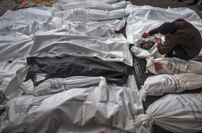 A man mourns over the shrouded bodies of his family members who were killed in an Israeli strike on a residential home in Rafah, January 2025. (AFP via Getty Images)
