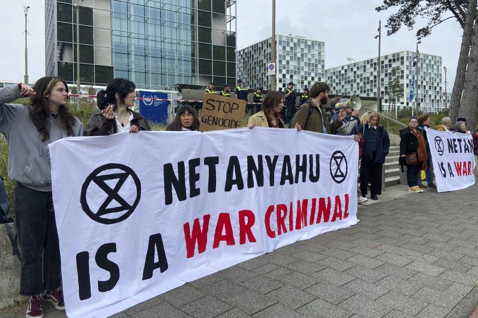 Activists hold up a banner denouncing Israeli Prime Minister Benjamin Netanyahu for Israeli genocide against Palestinians in Gaza as they demonstrate at the entrance of the International Criminal Court in The Hague, Netherlands, Monday, Oct. 23, 2023. (AP)
